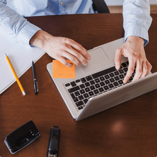 A man engaged in digital marketing work, typing on a laptop at a desk