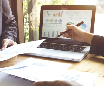 Digital Marketing professionals analyzing laptop graphs in a group setting